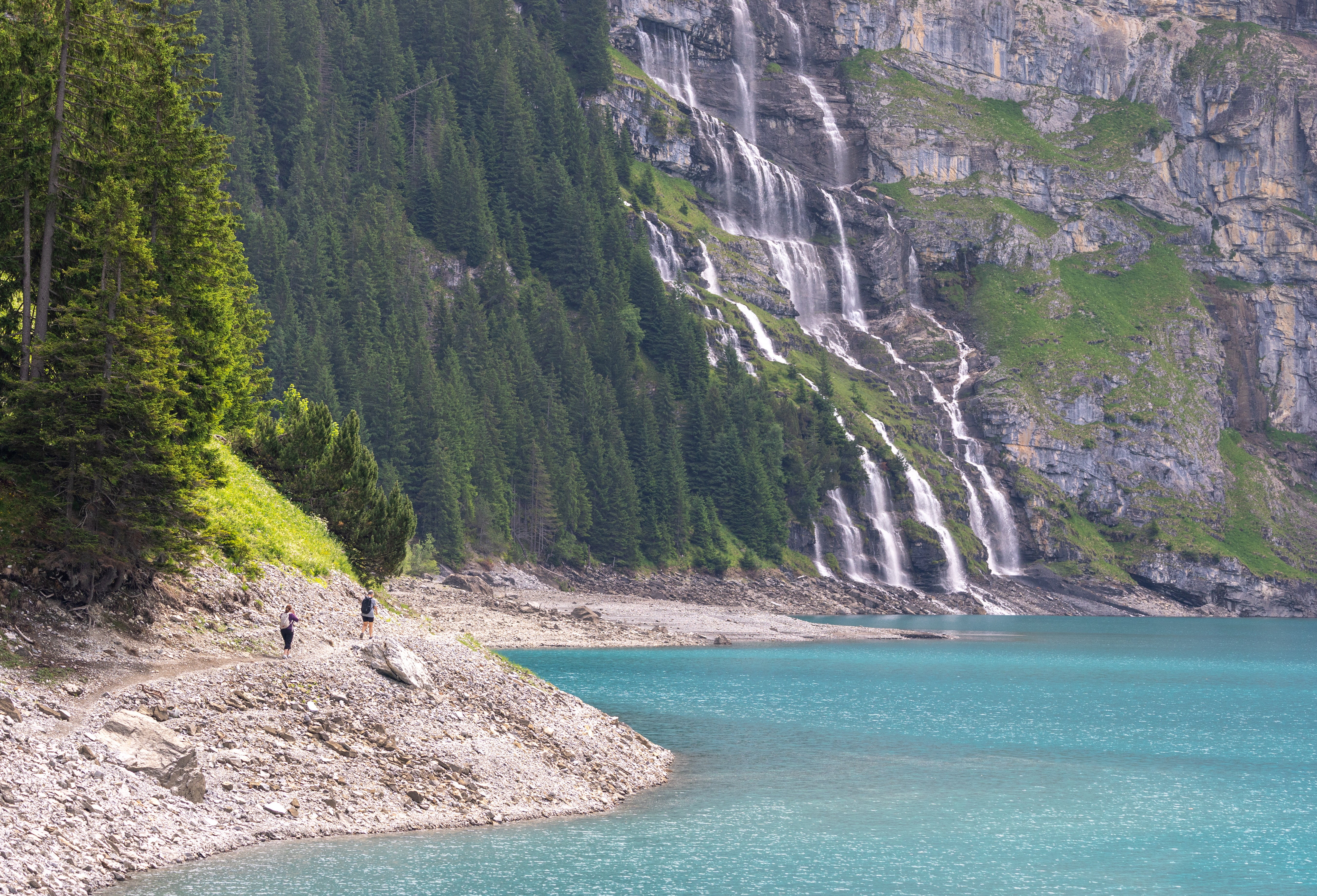 Hikers walk towards a waterfall at the Oeschinensee as rock falls from the Spitzen Stein threatens the village amid climate change and warming permafrost pose increasing challenges in Kandersteg, Switzerland, June 26, 2025. REUTERS/Denis Balibouse