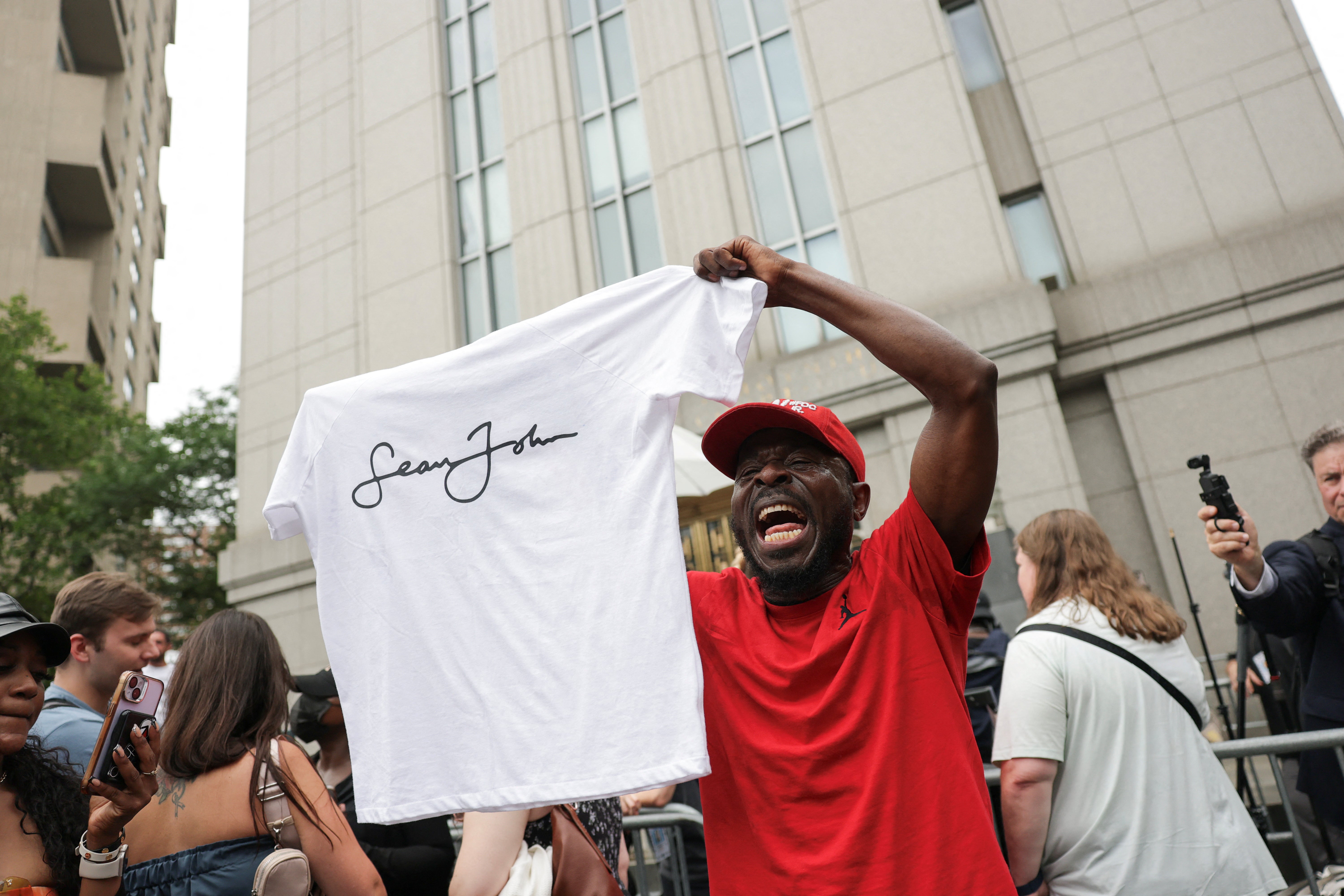 A man outside court holds a Sean John T-shirt, a company created by Combs