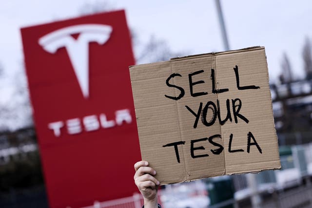 <p>A home-made sign is held up at a protest outside a Tesla dealership in Park Royal in west London on 22 March, 2025</p>