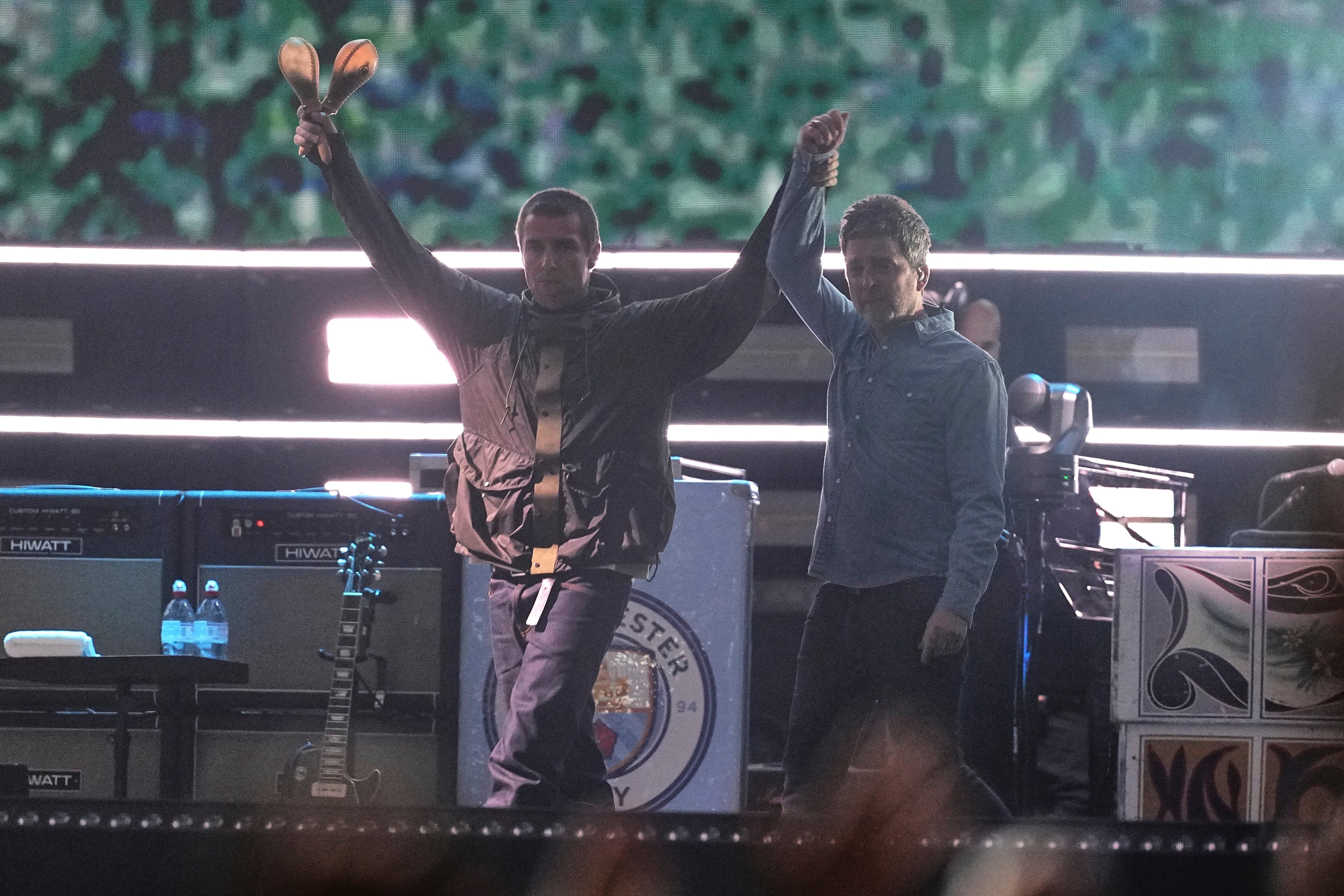 Noel and Liam Gallagher hold hands as they walk out on stage in Cardiff