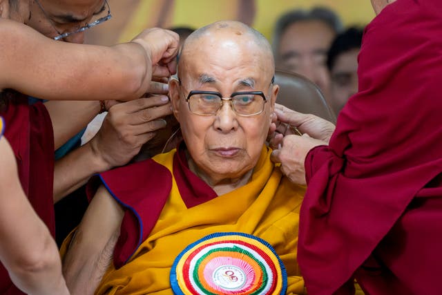 <p>Attendant monks help put a microphone around Tibetan spiritual leader the Dalai Lama's head during his 90th birthday celebrations at the Tsuglakhang temple in Dharamshala</p>