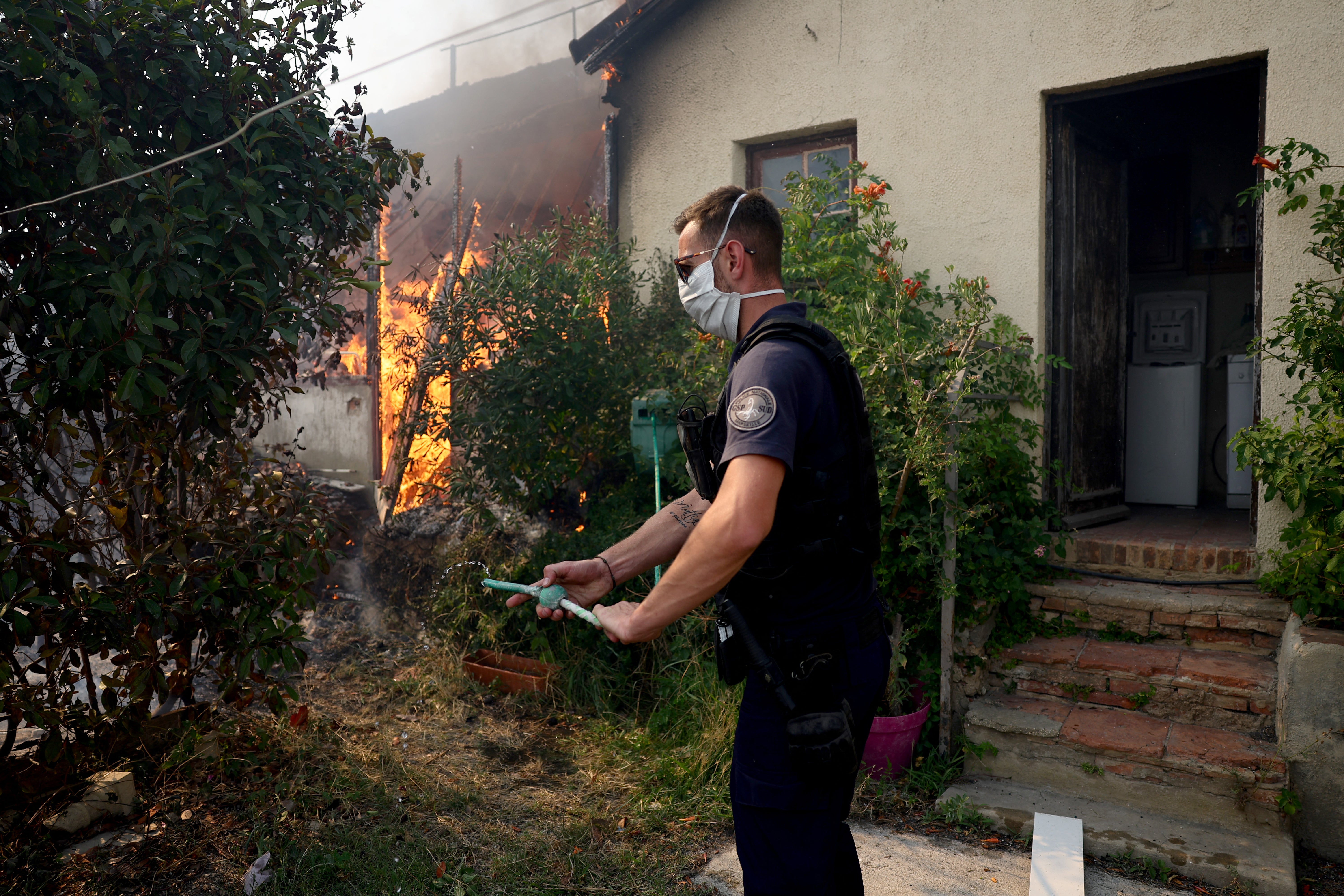 Police officers keep the hose while trying to turn off fire in Marseille