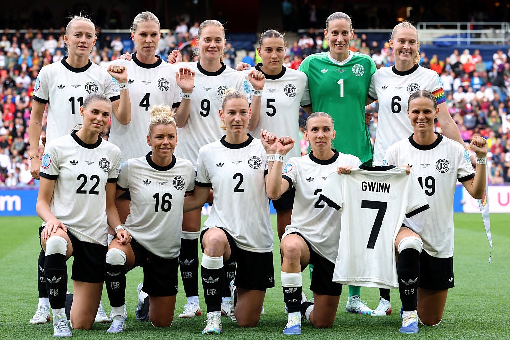 Players of Germany pose for a team photo while holding a shirt of Germany captain Giulia Gwinn, who suffered a medial ligament injury in Germany's 2-0 victory against Poland
