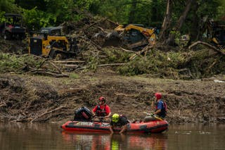 Search and rescue workers use a sonar device while paddling down the Guadalupe River in a boat looking for survivors or the remains of victims swept up in the flash flooding on 7 July 2025 in Hunt, Texas