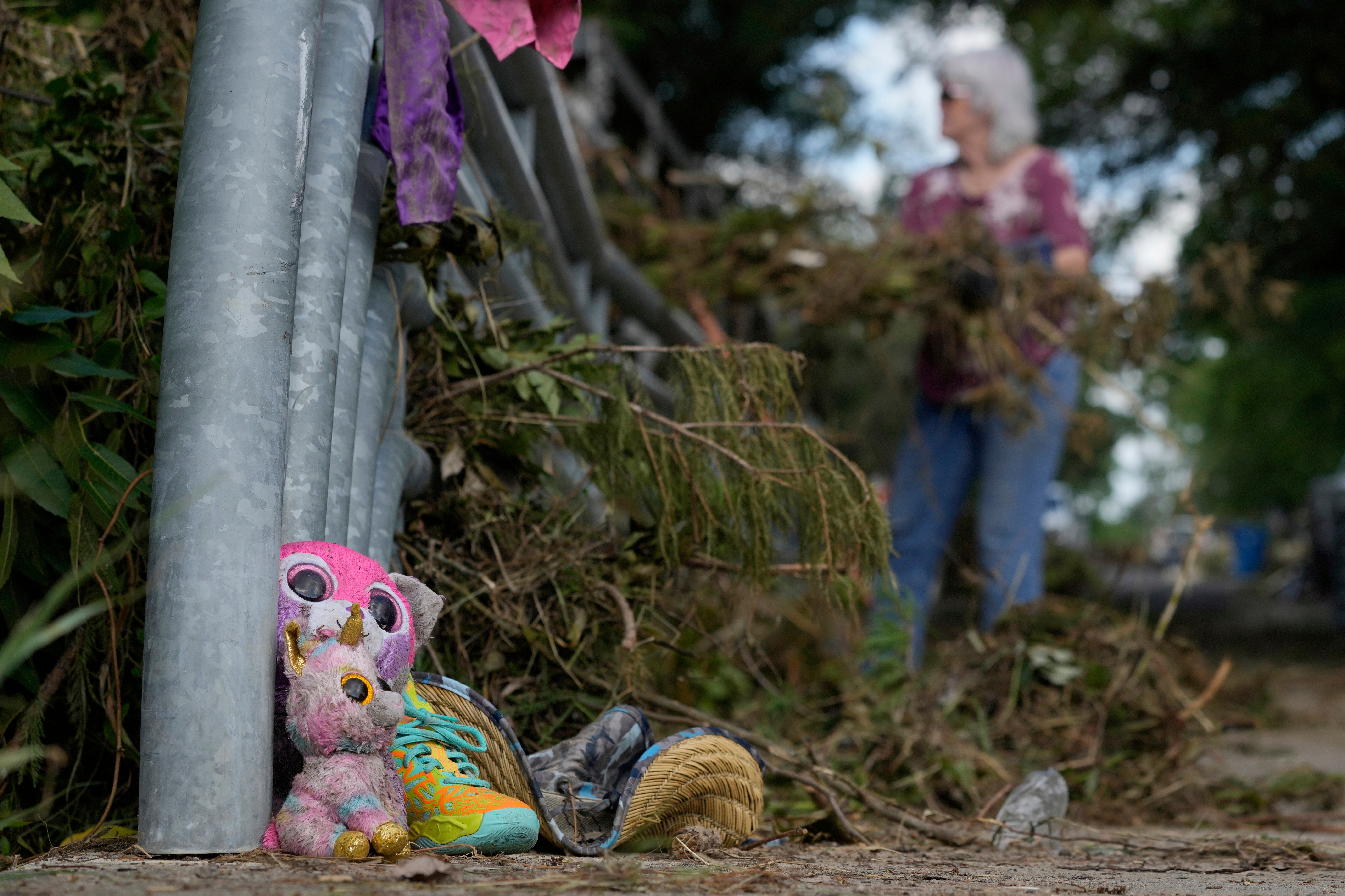 Lost items sit at a bridge as a volunteer cleans up debris on Tuesday