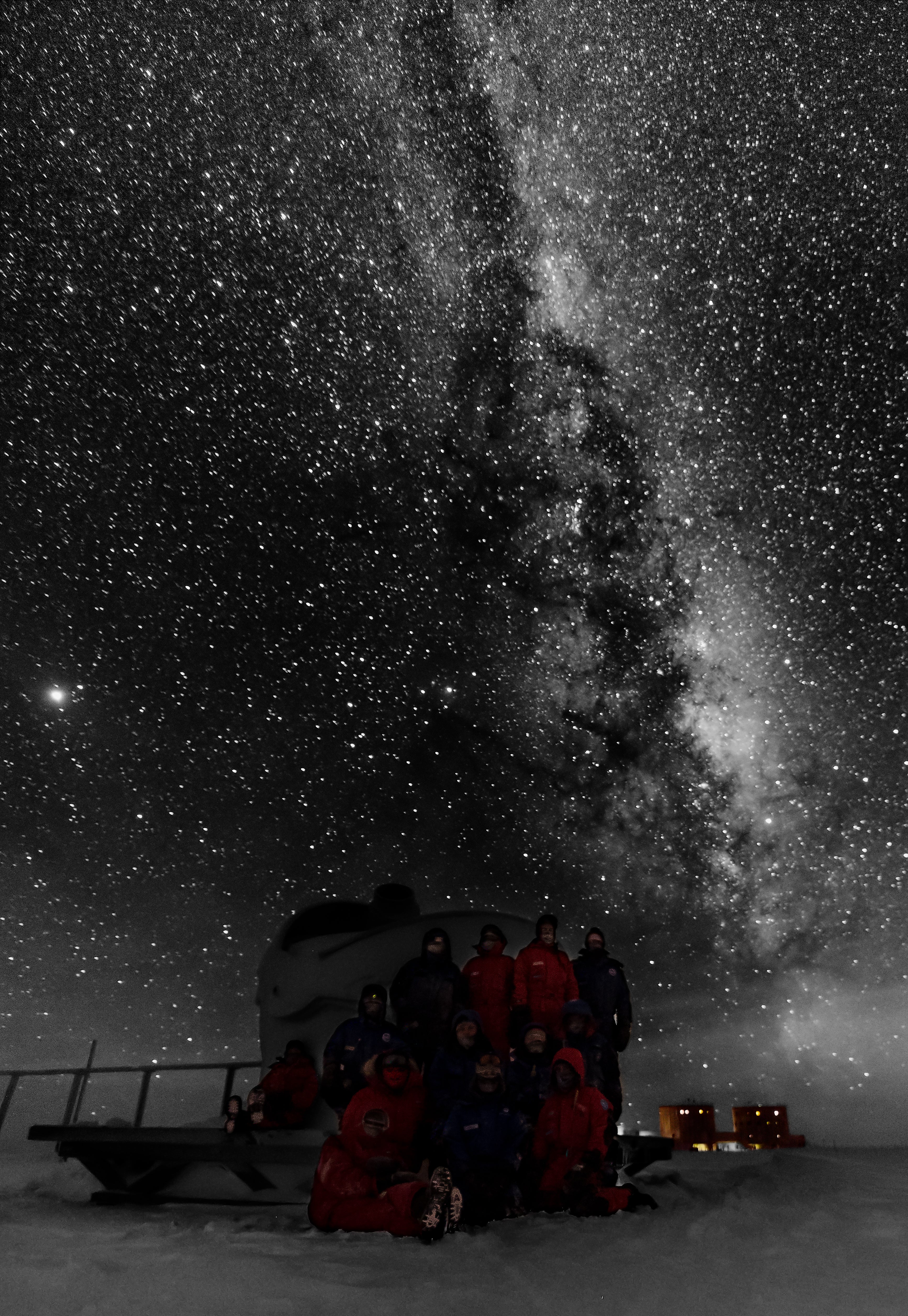Nowhere on earth can the night sky be seen as clearly as in interior Antarctica, where light pollution is nonexistent. Here, the winter-overing crew is gathered around a telescope and the base is in the background