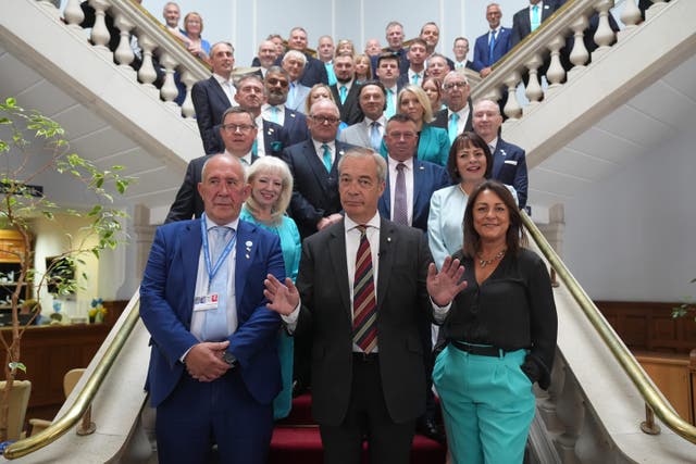 Reform UK leader Nigel Farage is accompanied by councillor Brian Collins (left) and the head of Kent County Council, Linden Kemkaran (right) as he poses for a photo with members of Kent County Council (PA)