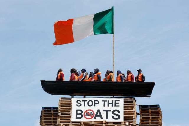 <p>A loyalist bonfire pyre is seen with a model effigy of a boat containing mannequins portrayed as migrants in lifejackets.</p>