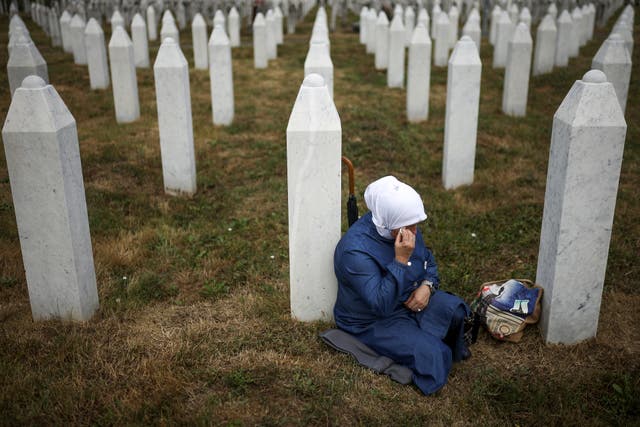 <p>A Bosnian Muslim woman mourns next to the grave of her relative, a victim of the Srebrenica genocide</p>
