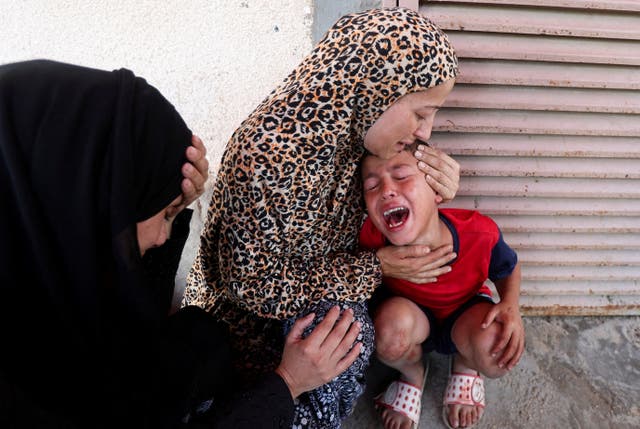 <p>Palestinian mother Samah Al-Nouri, whose daughter Sama was killed in the Israeli strike near the medical center in Deir Al-Balah, comforts her son, as casualties from the strike are brought into Al-Aqsa Martyrs Hospital</p>