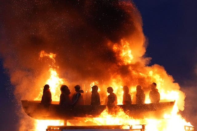 <p>A loyalist bonfire in Co Tyrone topped with effigies of migrants in a boat is set alight (Niall Carson/PA)</p>