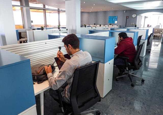 <p>People sit in office cubicles as they work </p>