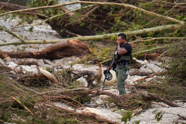 <p>A sheriff's deputy pauses while combing through debris on the banks of the Guadalupe River in Hunt, Texas after floods ravaged the area</p>