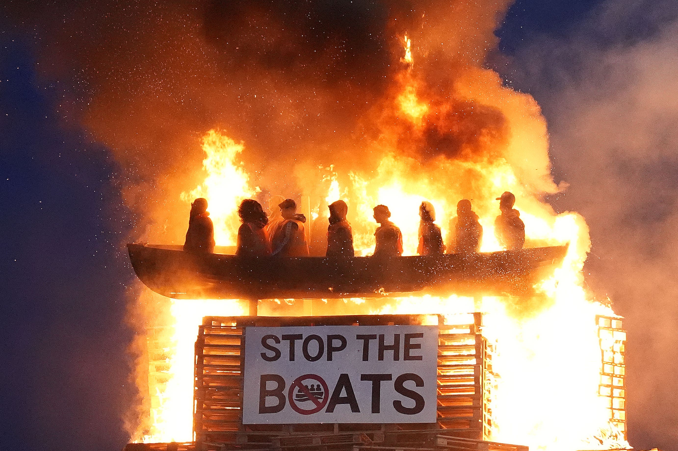 Effigies of migrants in a boat burn atop a bonfire at Moygashel, Co Tyrone (Niall Carson/PA)