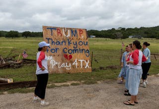 Volunteers who help locals clean the debris from their houses, place a banner on a main road ahead of U.S. President Donald Trump's travel to Texas to tour areas affected by deadly flash flooding, in Hunt, Texas