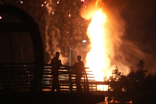 Police watch from a motorway flyover as a bonfire on Roden Street in Belfast is lit (Niall Carson/PA)