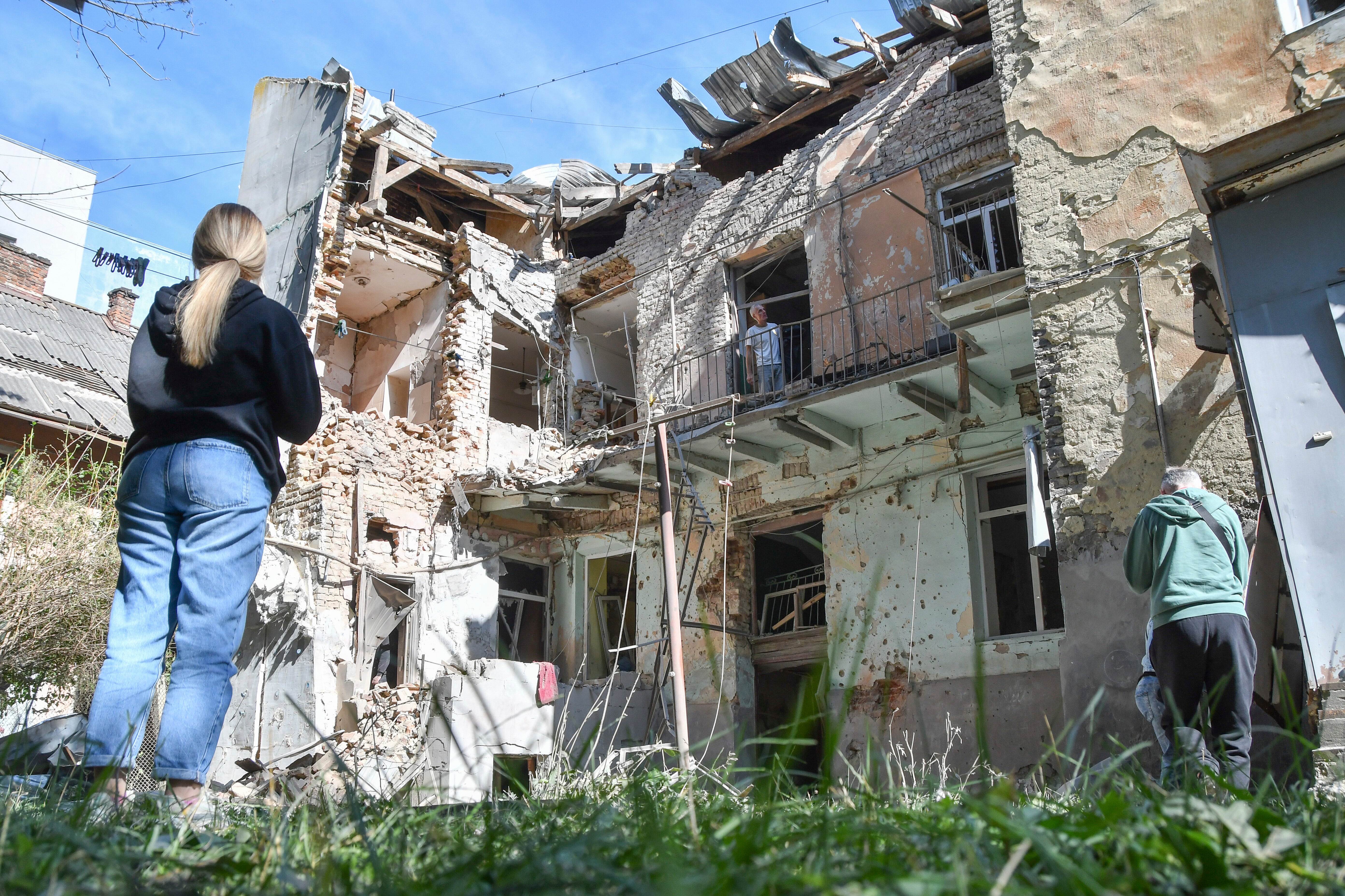 People look at a damaged residential building following Russian air attack in Lviv on Saturday