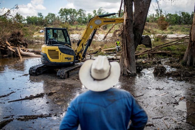 <p>A person watches as machinery is used to clear debris along the banks of the Guadalupe River after catastrophic floods in Center Point, Texas</p>