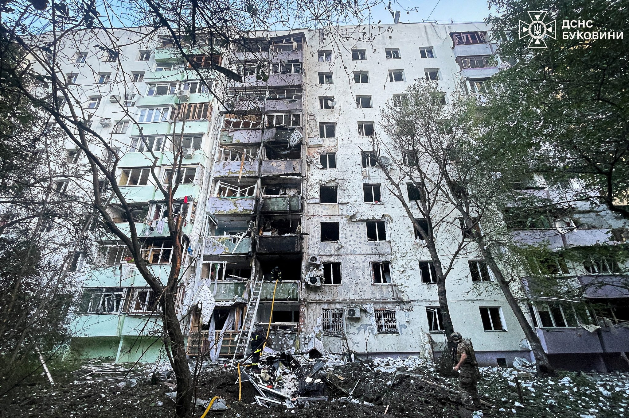 Firefighters and a police officer work at the site of an apartment building damaged during Russian drone and missile strikes