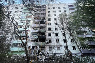 Firefighters and a police officer work at the site of an apartment building damaged during Russian drone and missile strikes on Saturday