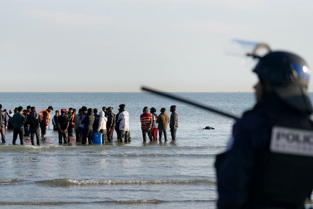 People thought to be migrants wade through the sea to board a small boat leaving the beach at Gravelines, France (Gareth Fuller/PA)