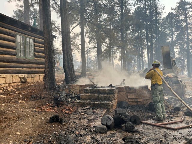 <p>A firefighter stands near smoldering debris near the Grand Canyon Lodge</p>