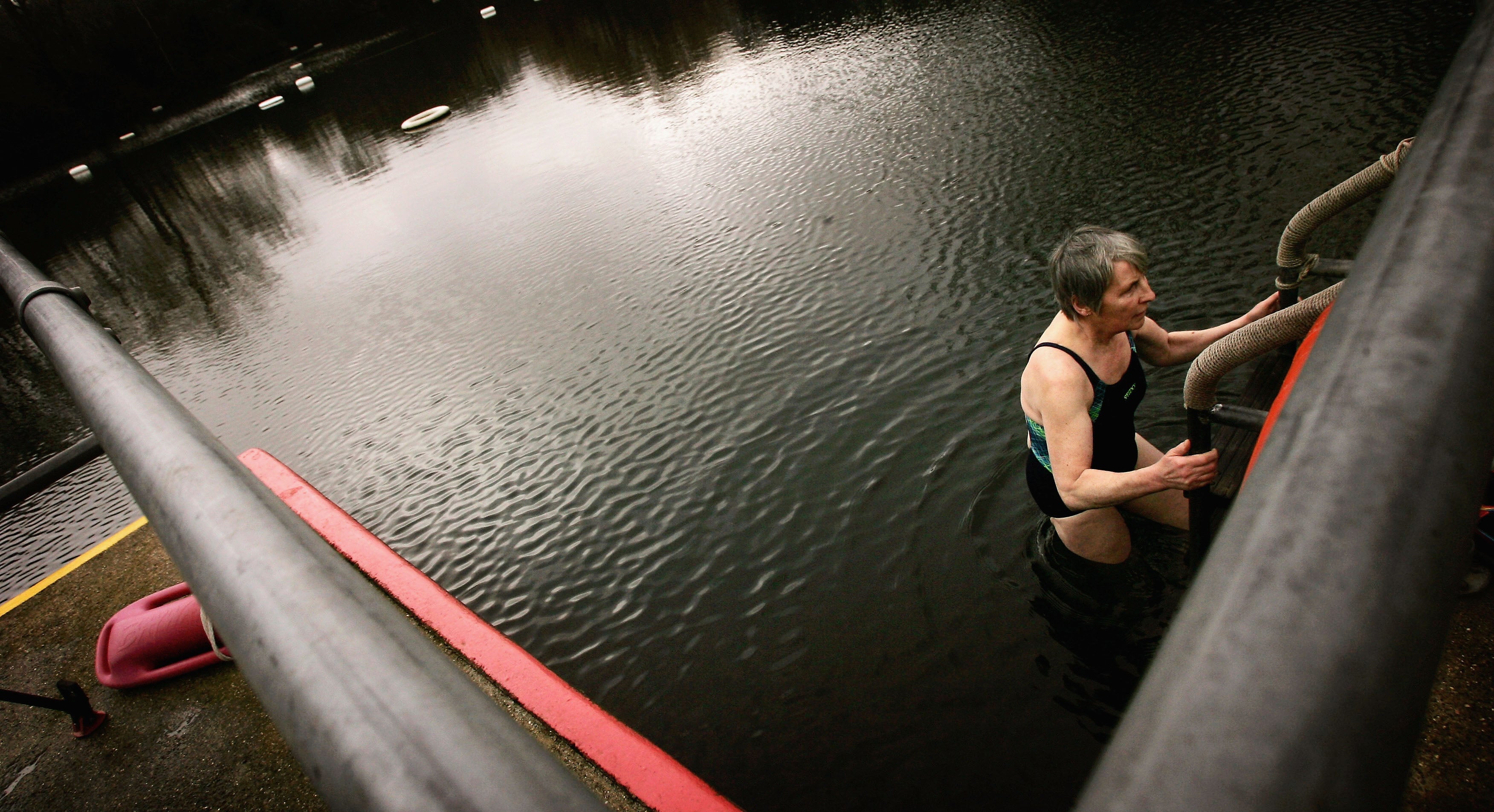 A woman climbs out of the Kenwood Ladies’ Pond during Winter in Hampstead Heath