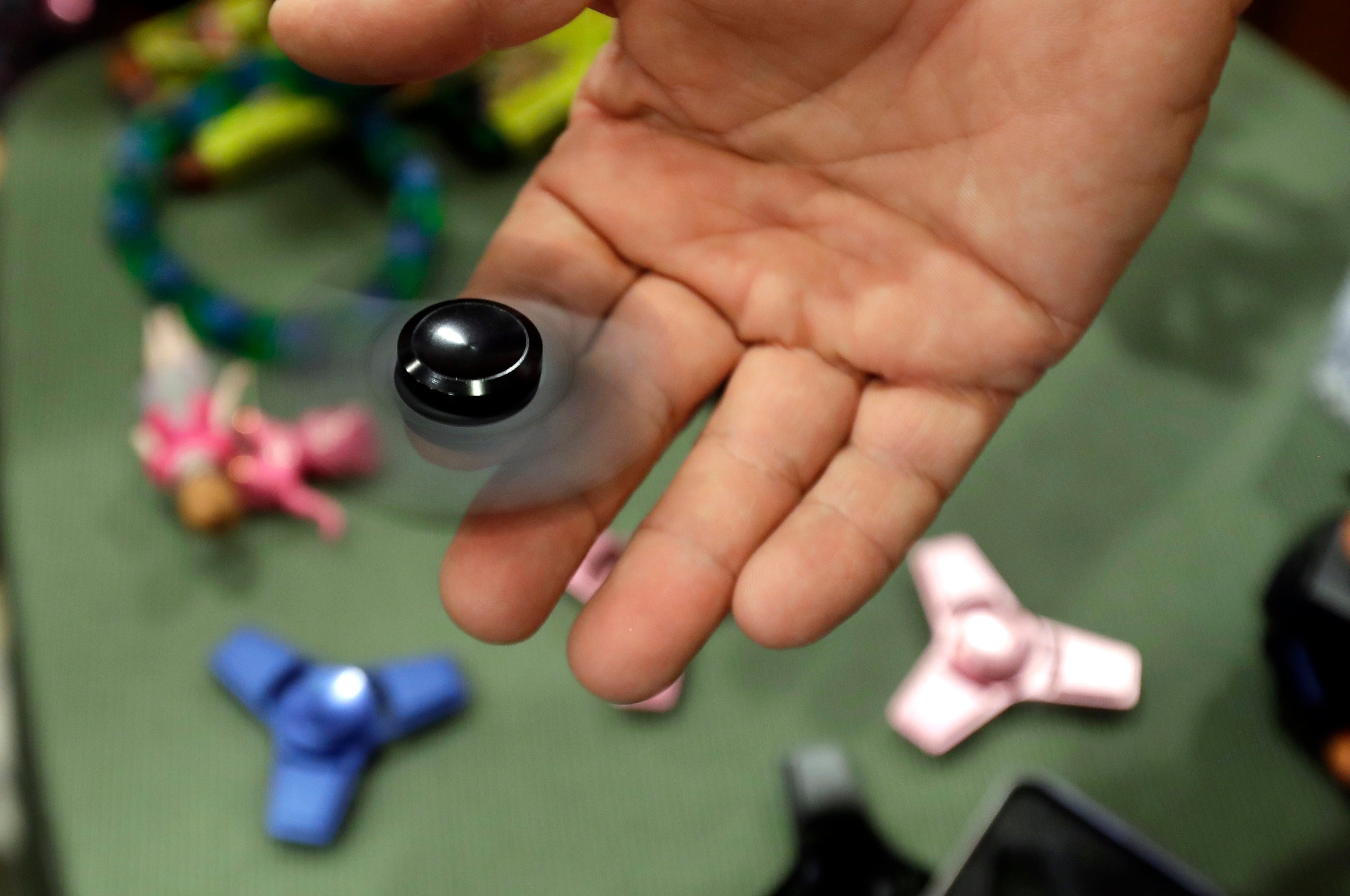 Funky Monkey Toys store owner Tom Jones plays with a fidget spinner in Oxford, Mich, Thursday, May 11, 2017. (AP Photo/Carlos Osorio, File)
