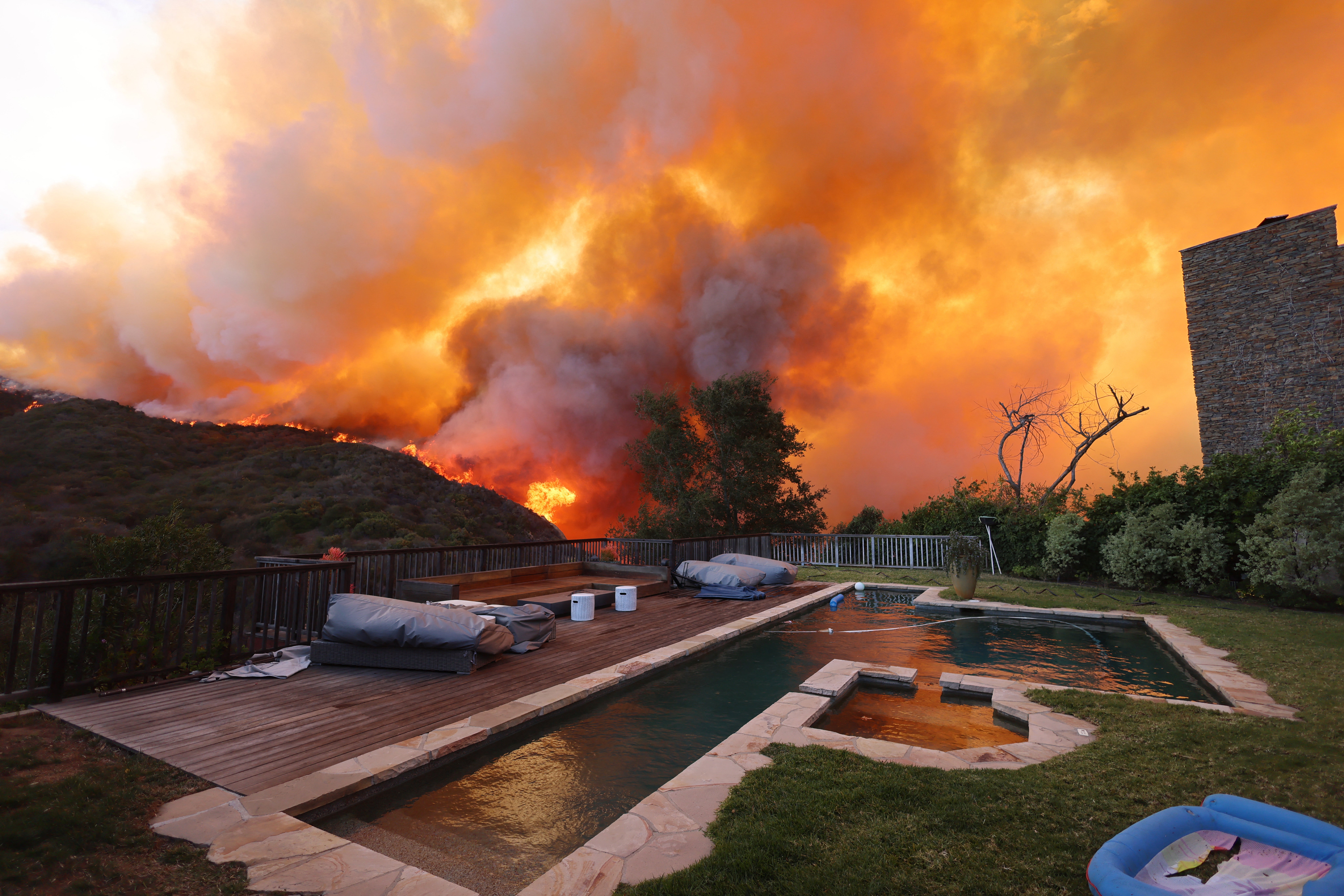A brush fire burns near homes in Pacific Palisades, California on January 7