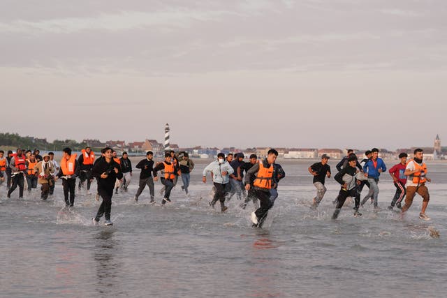 <p>People thought to be migrants run across the beach in Gravelines, France, in a bid to board a small boat (Gareth Fuller/PA)</p>