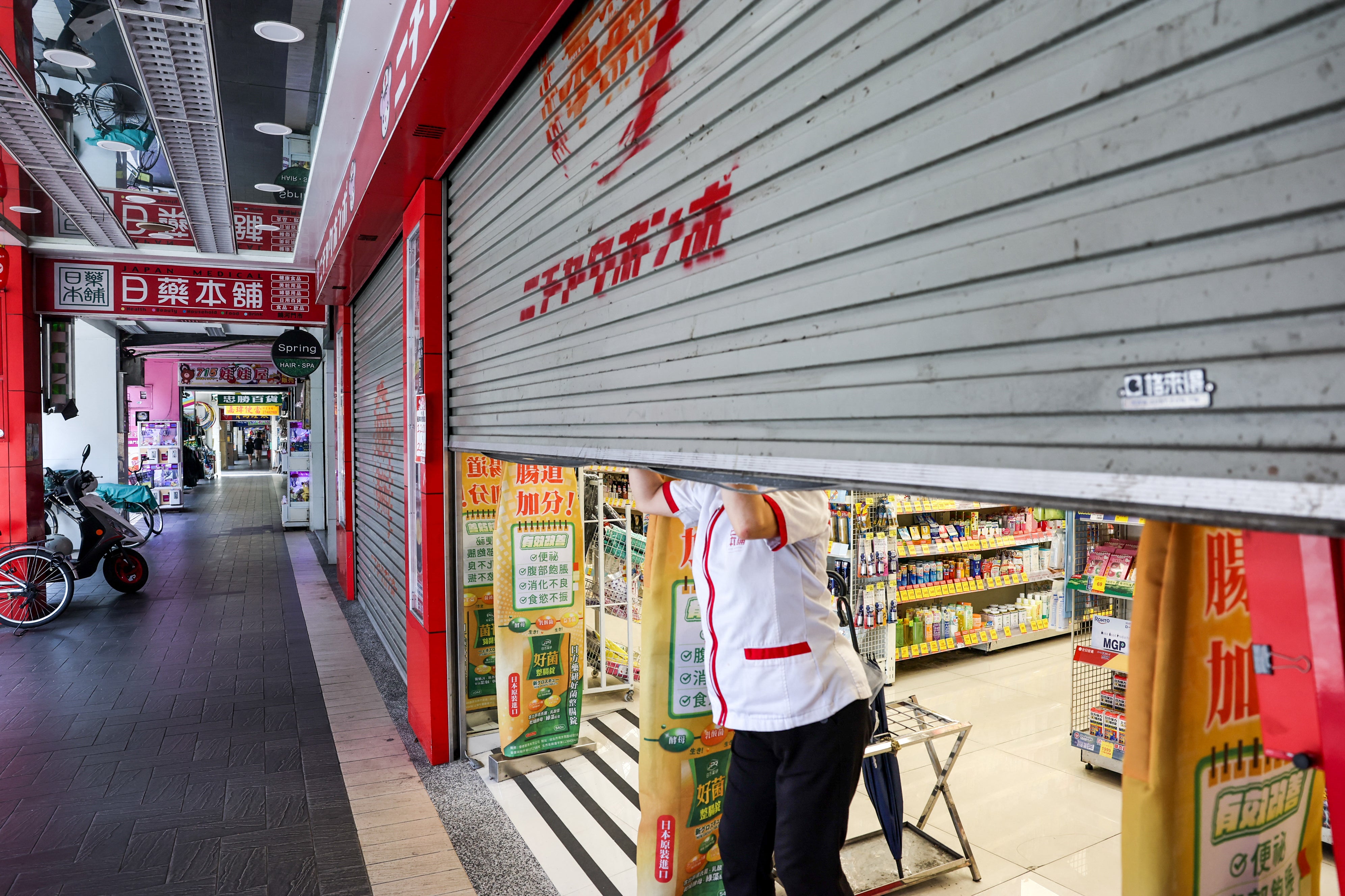 A store employee shutters a shop before an air raid drill coinciding with the Han Kuang military exercises in Taipei