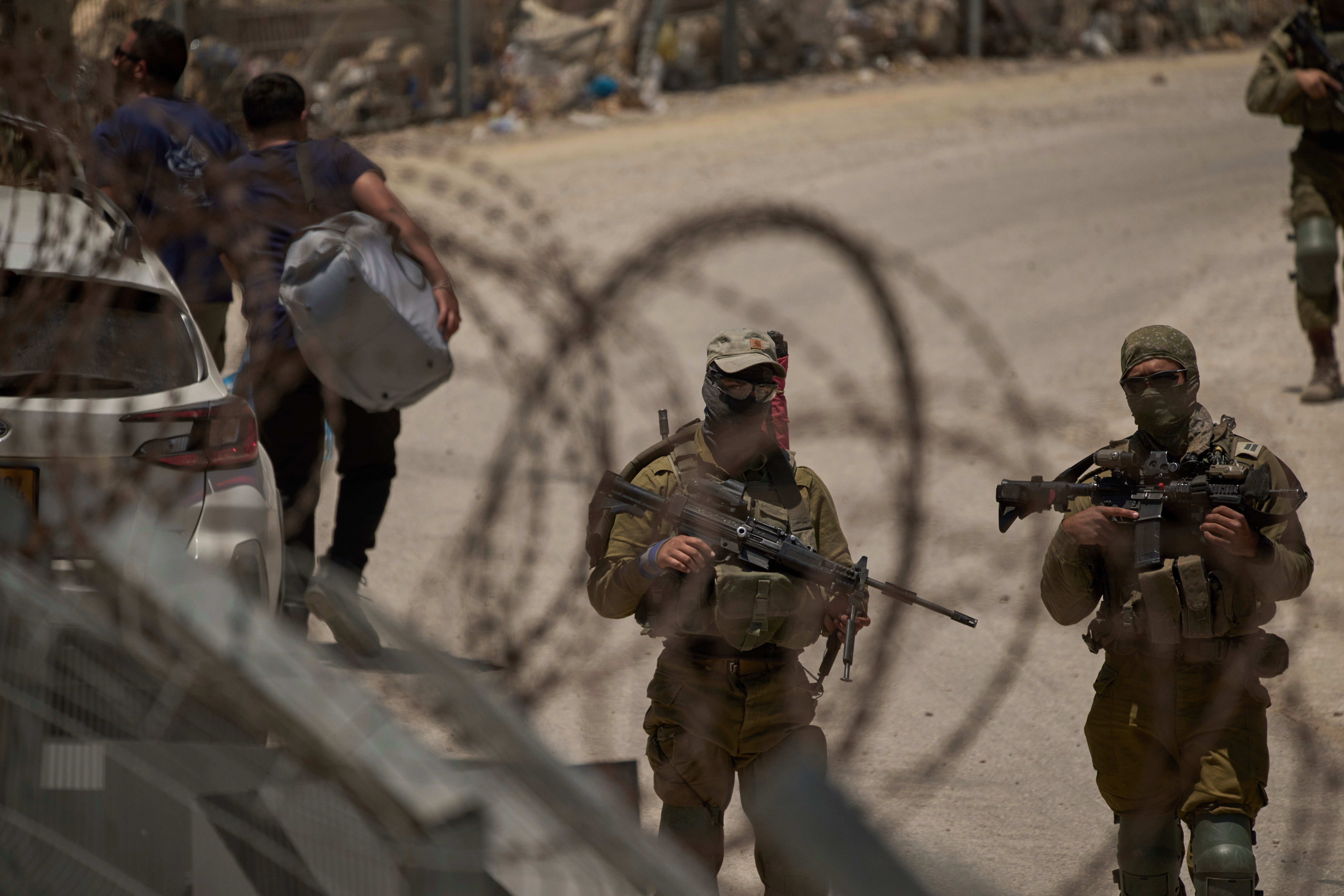 Israeli soldiers stand guard as Syrian Druze people cross back into Syria at the Israeli-Syrian border, in the Israeli-controlled Golan Heights town of Majdal Shams on 17 July