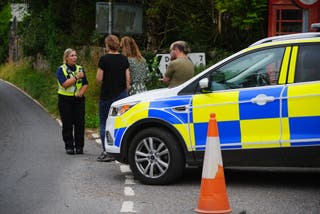 A police officer speaks to concerned locals near the site of the crash (Ben Birchall/PA)