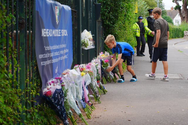 Two boys lay flowers at the entrance to Minehead Middle School in Somerset after a child died following a crash on Thursday (Ben Birchall/PA)