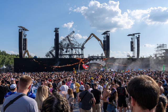 <p>Festival-goers gather before the burnt main stage during its dismantling on Friday</p>