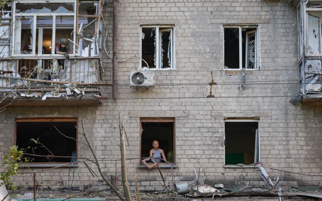<p>A woman removes broken glass from a window in the aftermath of recent shelling in Donetsk</p>