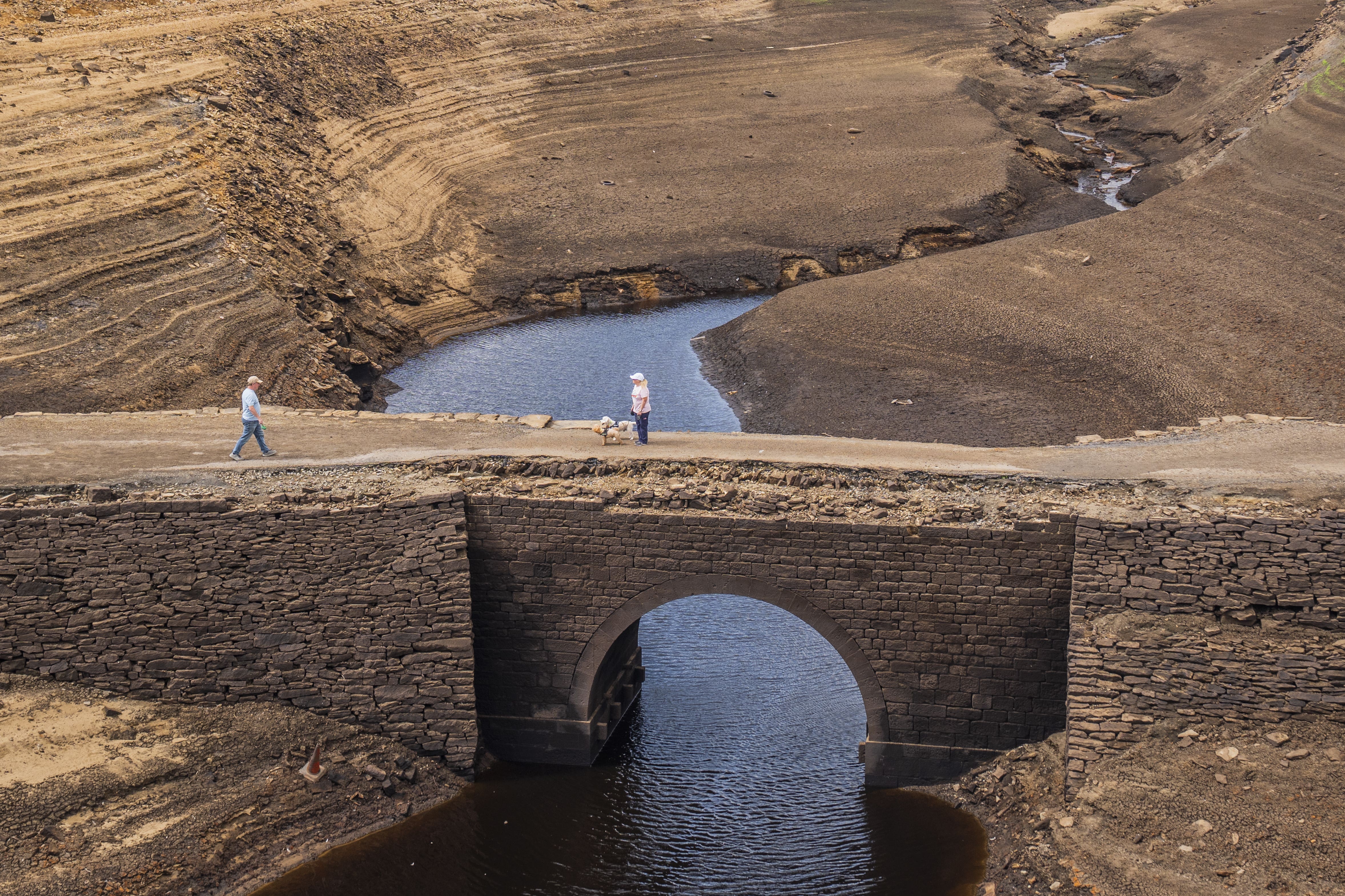 People walk over a bridge that is normally submerged by Baitings Reservoir in Ripponden, West Yorkshire (Danny Lawson/PA)