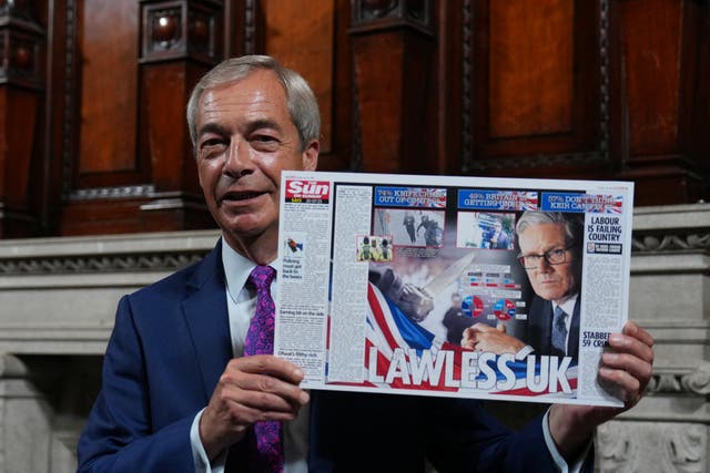 <p>Nigel Farage poses with an article by The Sun at a press conference in London on Monday</p>