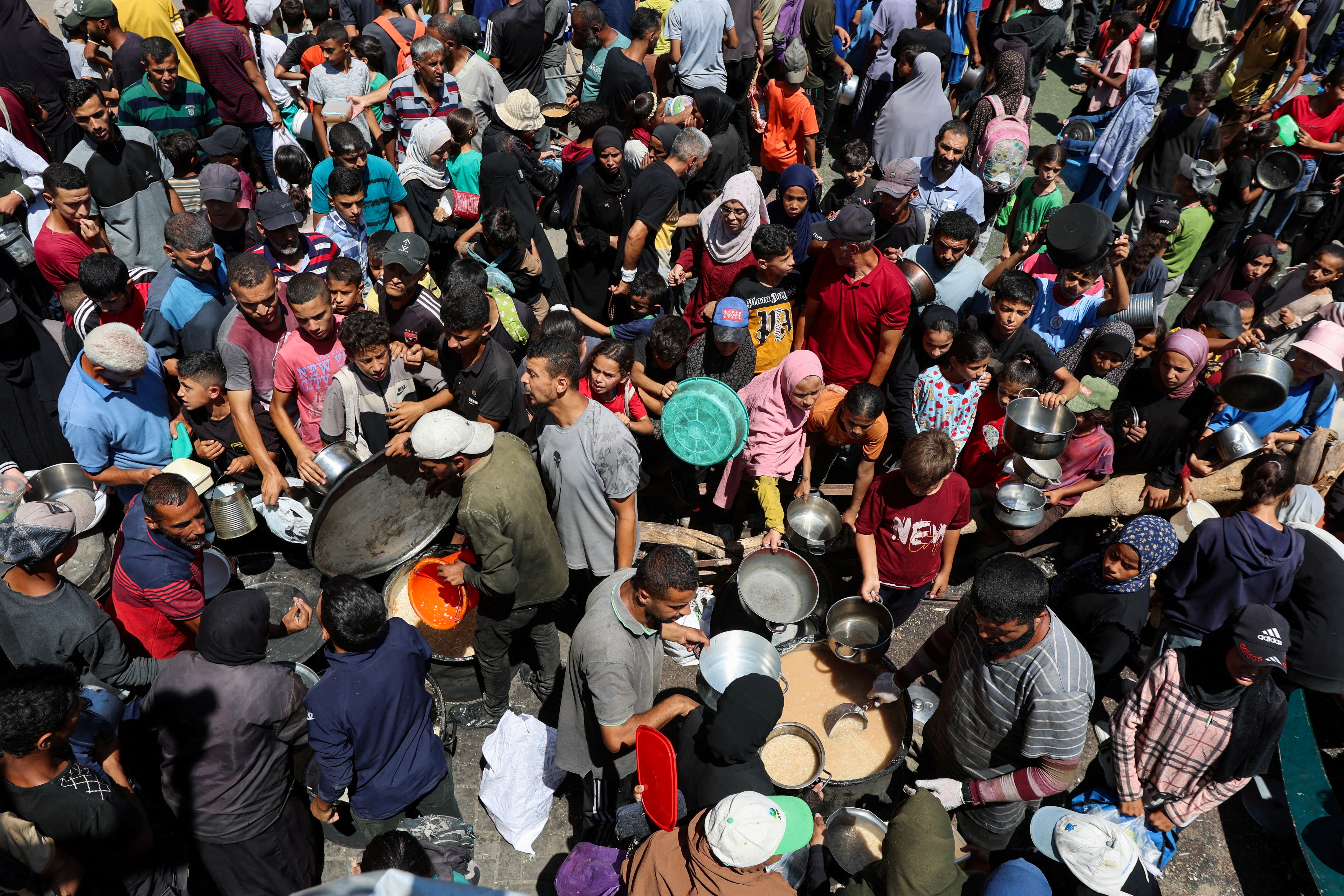 Palestinians gather to receive food from a charity kitchen in Nuseirat, central Gaza Strip