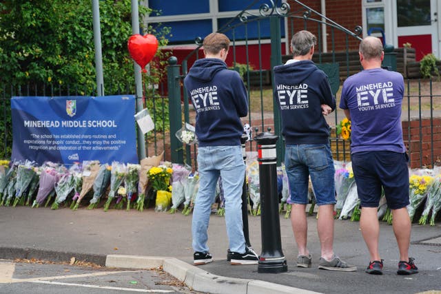 People look at floral tributes at the entrance to the Minehead Middle School (Ben Birchall/PA)