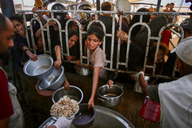 <p>Palestinians queue to receive a hot meal at a charity kitchen in Khan Younis, southern Gaza Strip, on Tuesday</p>