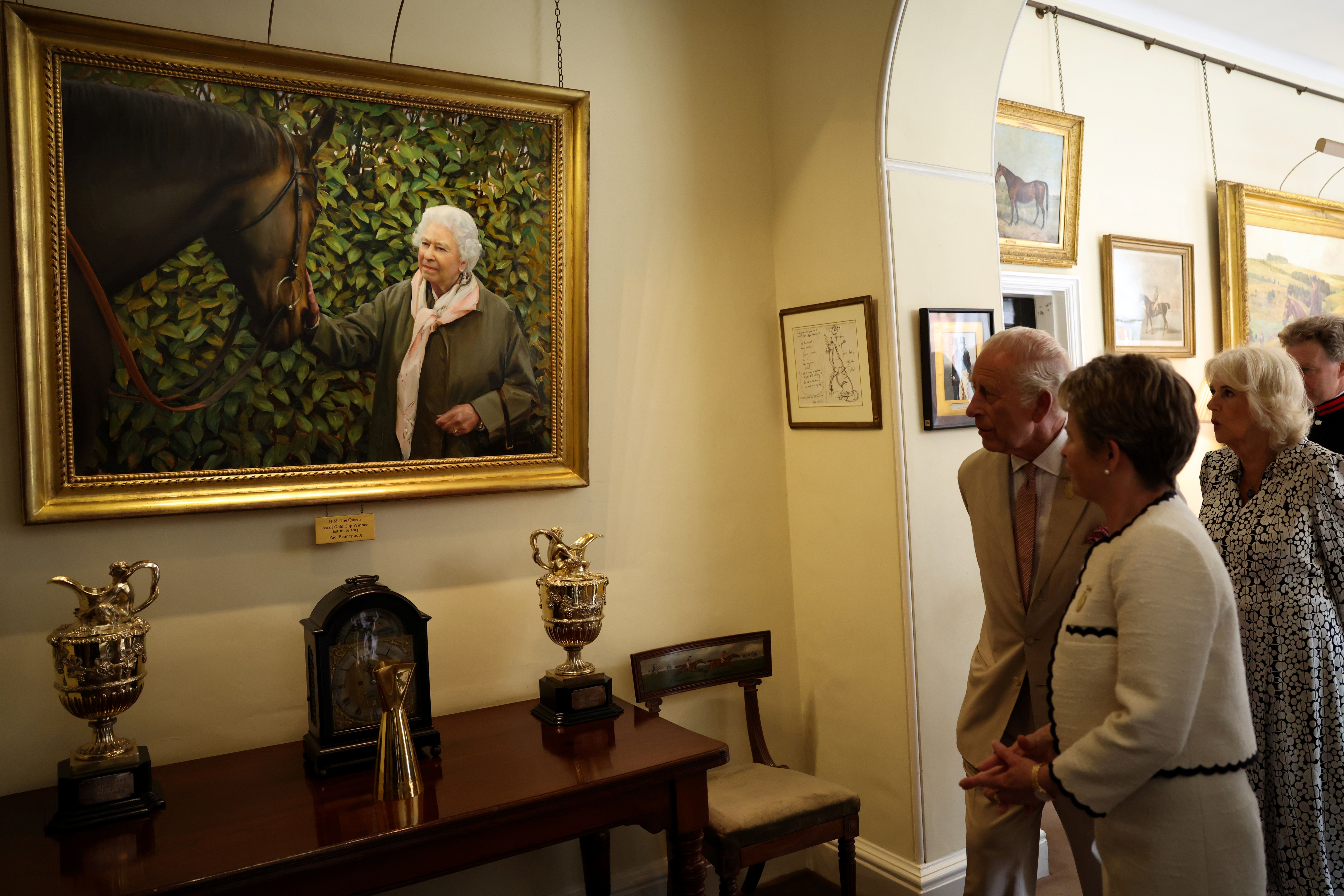 Charles and Camilla with senior steward of The Jockey Club Baroness Diana Mary Harding of Winscombe, look at a painting of the late Queen during a visit to the Jockey Club Rooms in Newmarket, Suffolk (Darren Staples/PA)