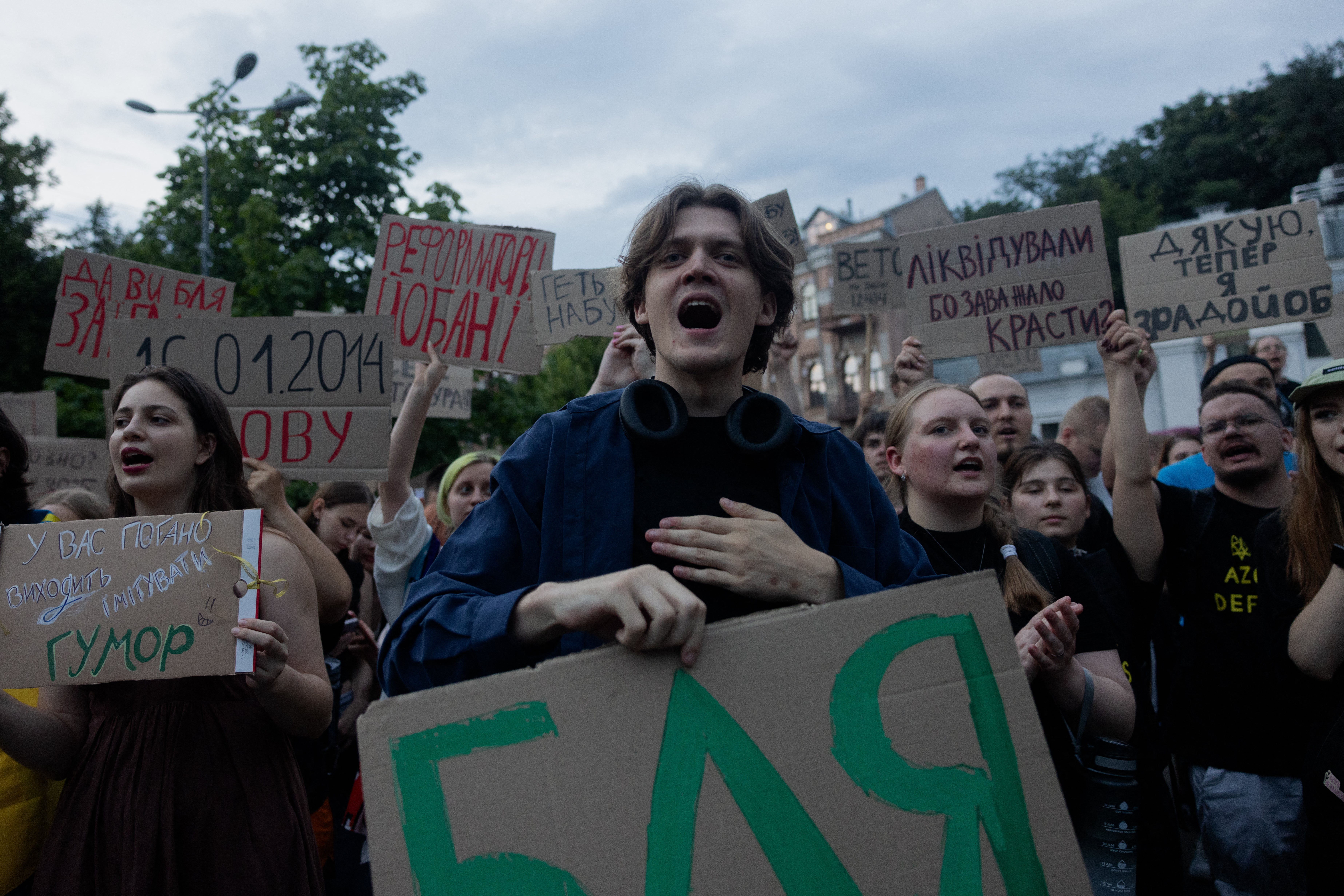 Protesters hold placards during a demonstration calling for the Ukrainian president to veto a law passed by parliament that reduces the powers of Ukraine's National Anti-Corruption Bureau (NABU) and Specialised Anti-Corruption Prosecutor's Office (SAPO) in downtown Kyiv