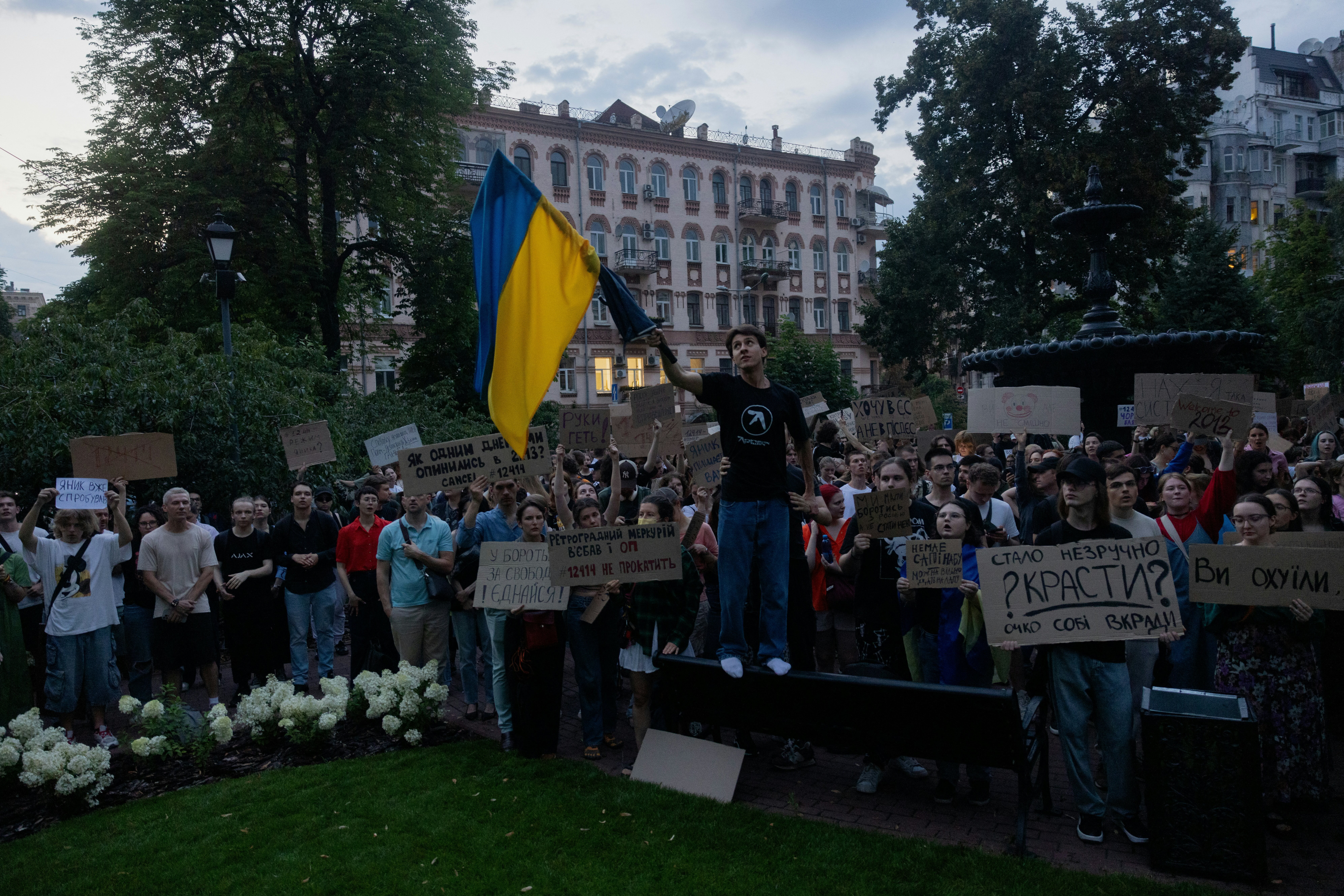 Protesters hold a national flag and placards during a demonstration calling for the Ukrainian president to veto a law passed by parliament that reduces the powers of Ukraine's National Anti-Corruption Bureau (NABU) and Specialised Anti-Corruption Prosecutor's Office (SAPO) in downtown Kyiv