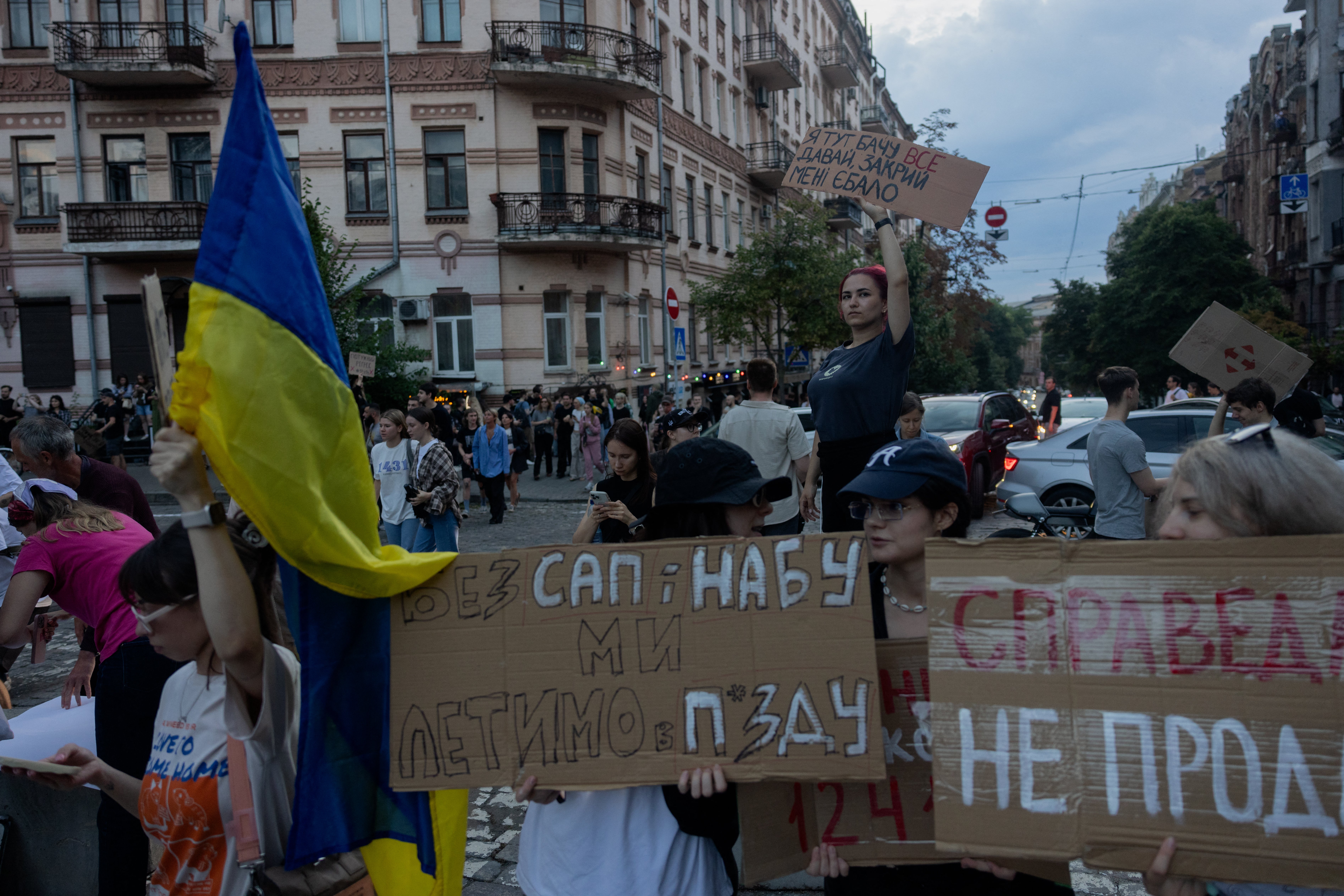 Protesters hold placards during a demonstration calling for the Ukrainian president to veto a law passed by parliament that reduces the powers of Ukraine's National Anti-Corruption Bureau (NABU) and Specialised Anti-Corruption Prosecutor's Office (SAPO) in downtown Kyiv