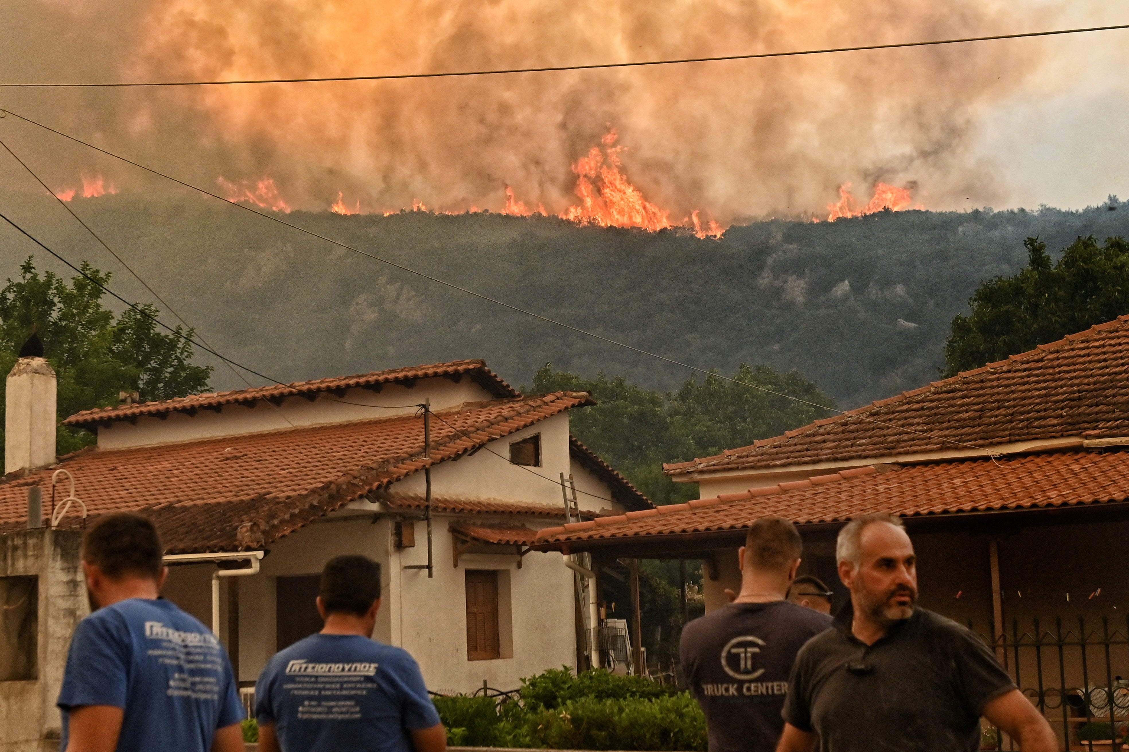 Residents watch flames rise from a wildfire burning next to the village of Karteri, in Feneos area, near Corinth, Greece, July 22, 2025. REUTERS/Vassilis Psomas