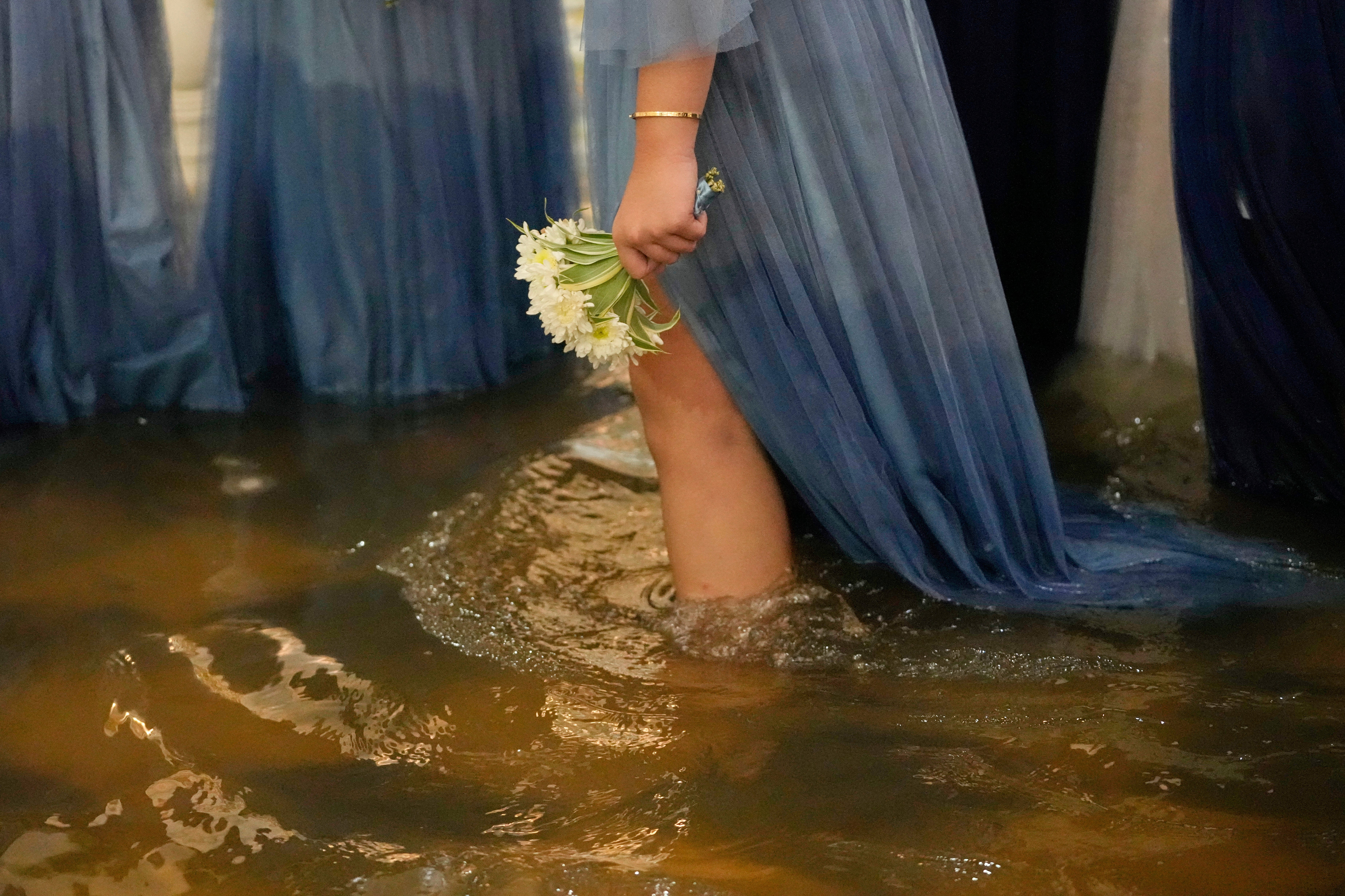 A wedding guest holds a flower during the wedding at the flooded Barasoain church in Malolos, Bulacan province, Philippines on Tuesday, 22 July 2025