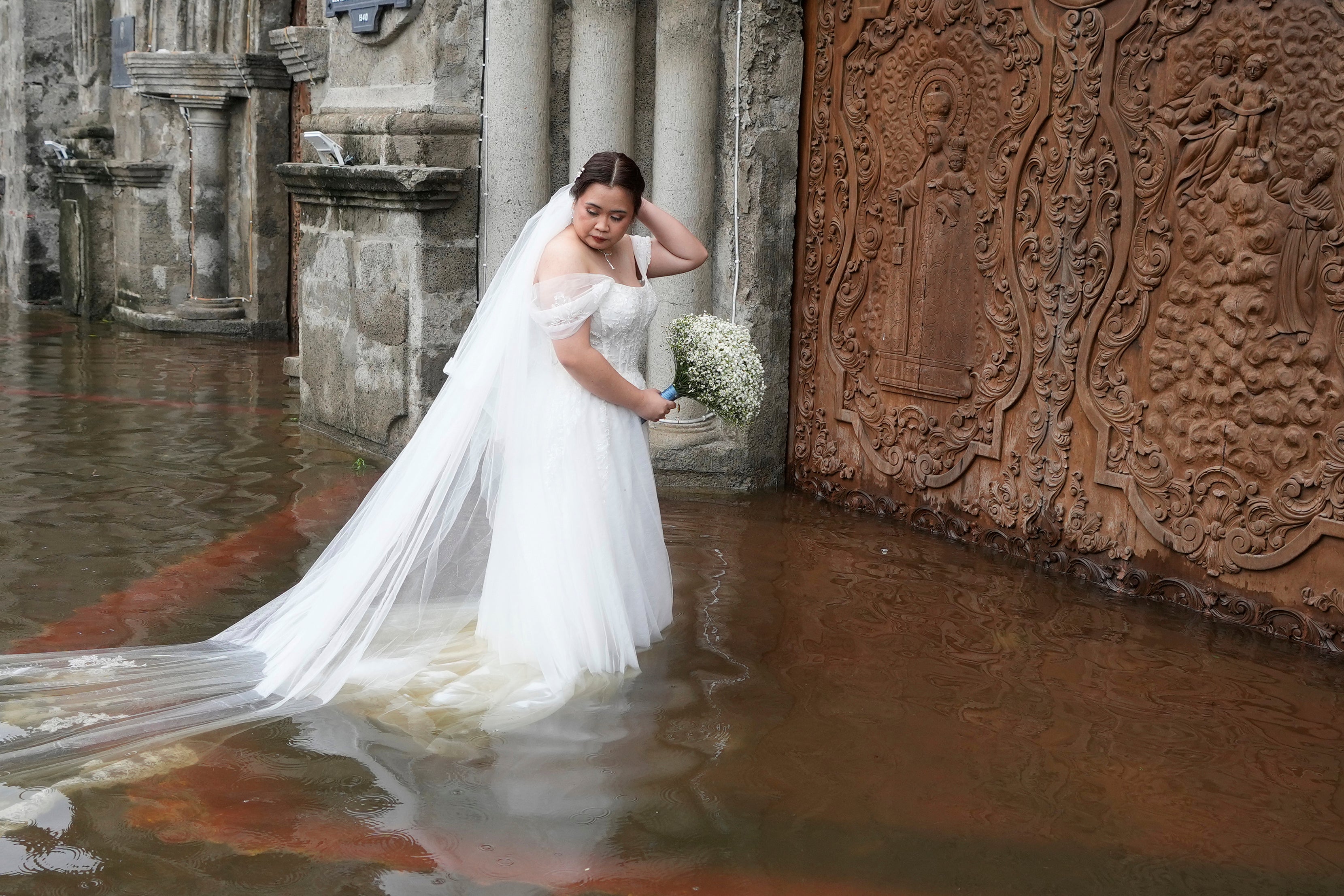 Bride Jamaica Agular prepares to enter the flooded Barasoain church for her wedding in Malolos, Bulacan province, Philippines on Tuesday, 22 July 2025