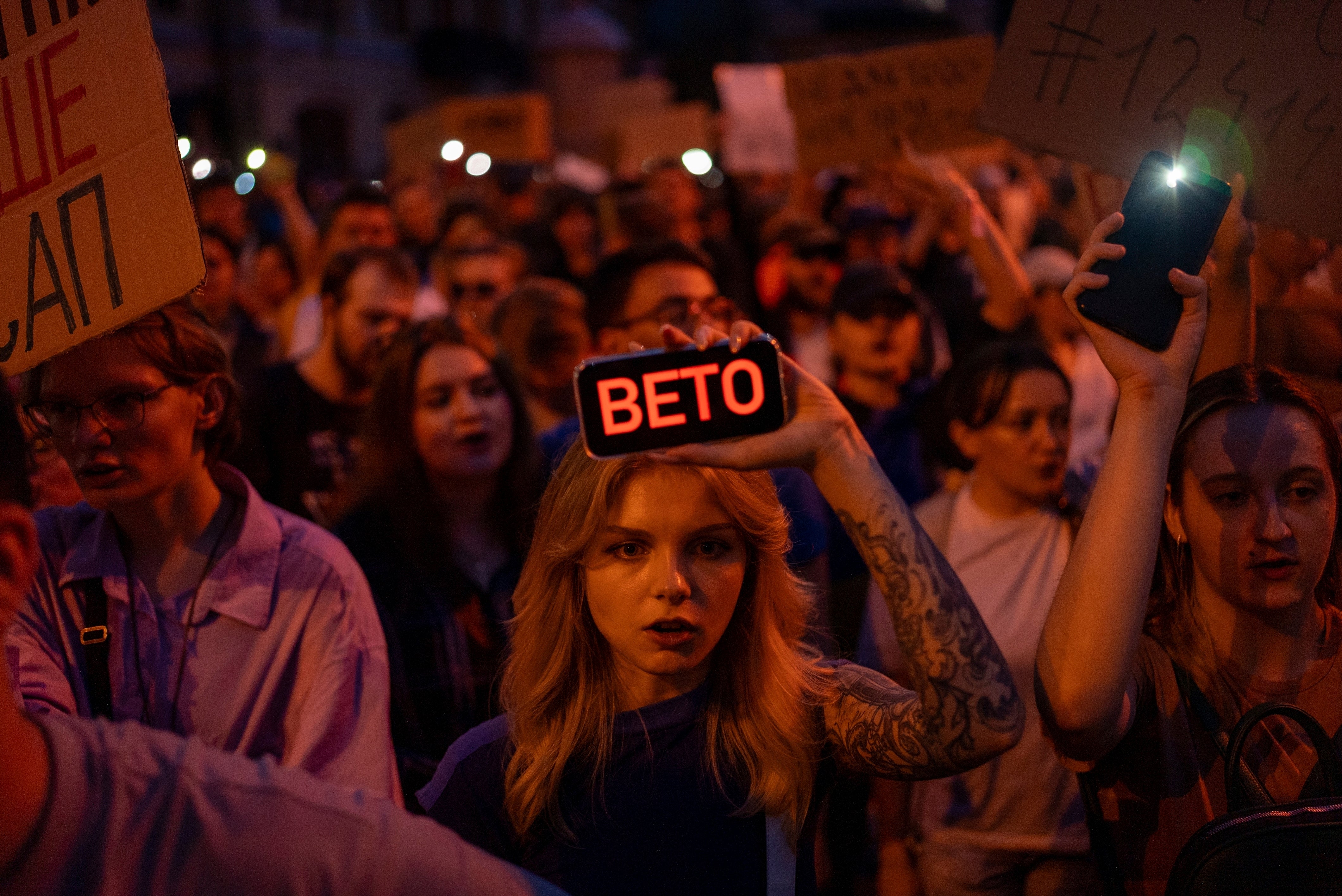 <p>A woman holds a phone with a sign reads ‘Veto’ during the protest against the law aimed towards regulations of anti-corruption institutions in central Kyiv</p>