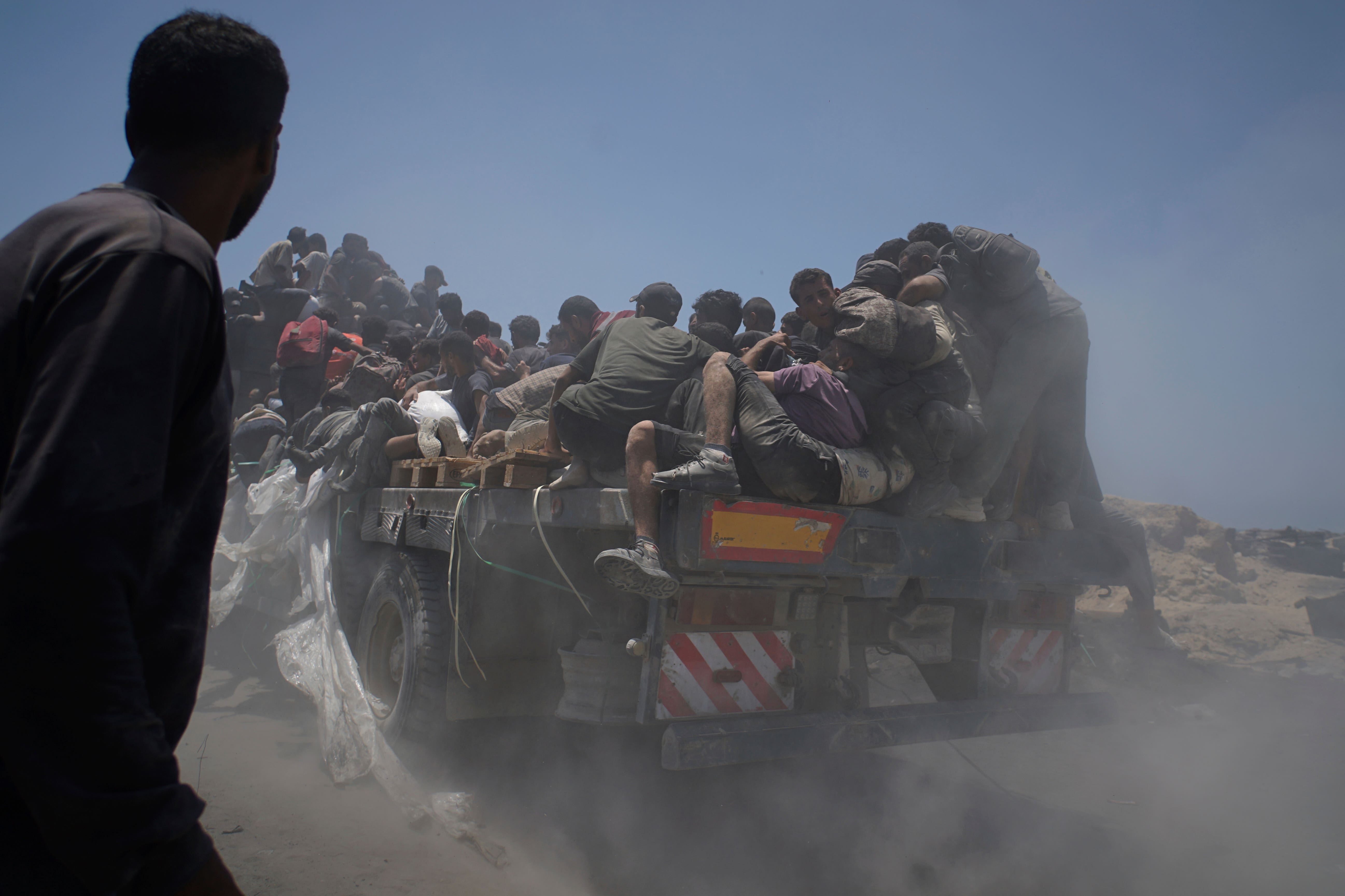 Palestinians hold on to an aid truck returning to Gaza City from the northern Gaza Strip on Tuesday (Jehad Alshrafi/AP)